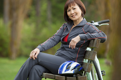 image shows mature woman sitting on park bench
